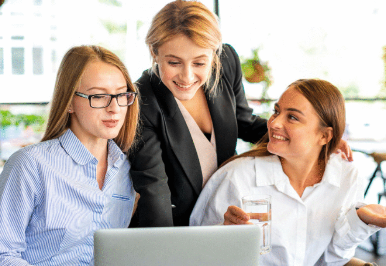 Women collaborating in a coworking space in Hyderabad, discussing work on a laptop.