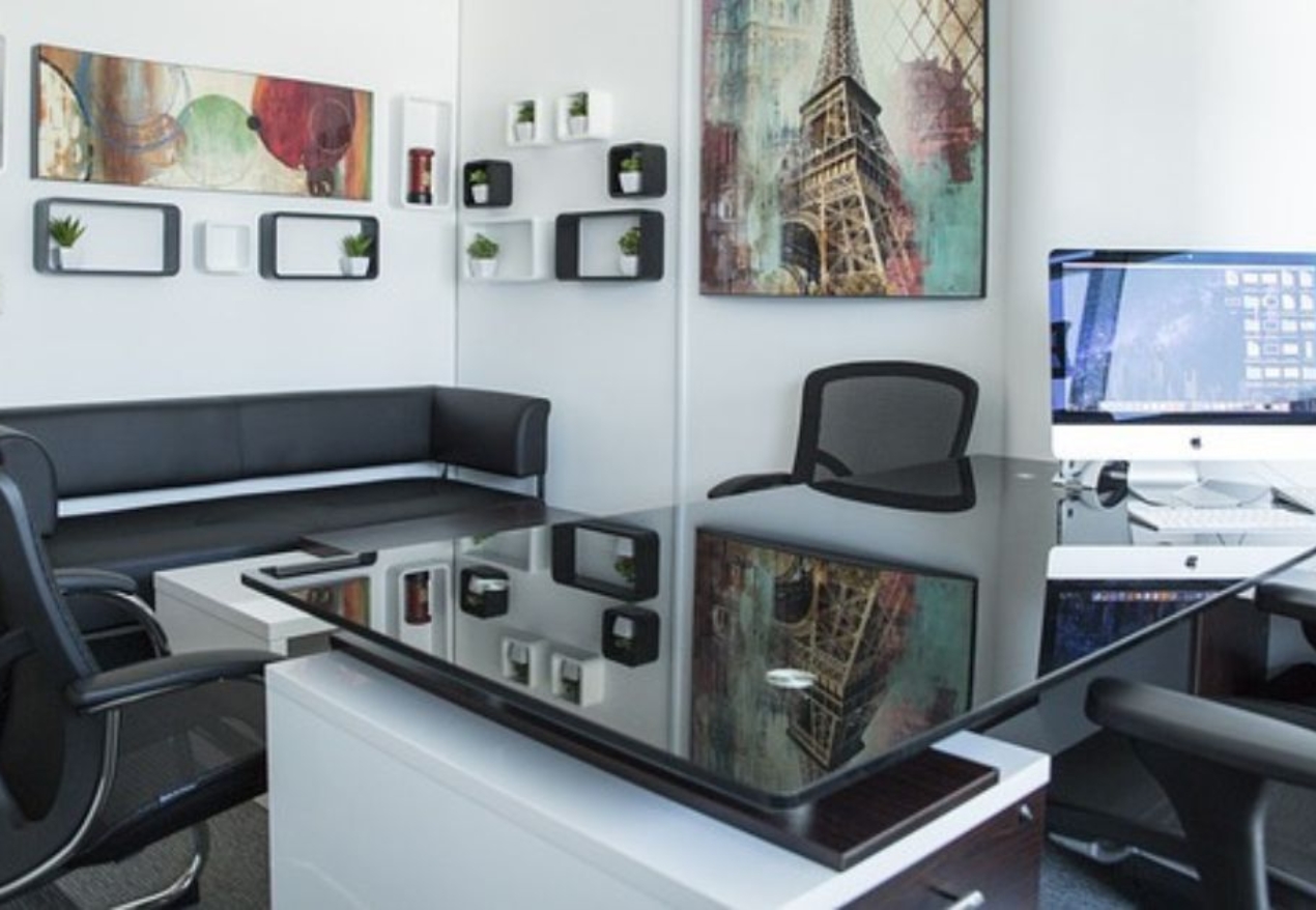 A modern furnished office space with sleek black furniture, a glass-top desk, and stylish wall decor. Fully furnished office in Hyderabad with a professional and elegant setup.