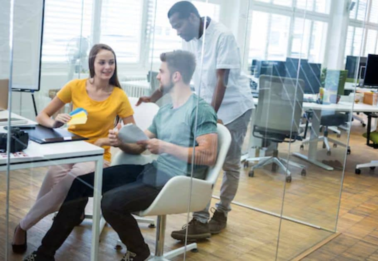 Young professionals collaborating in a modern coworking space in Hyderabad, featuring an open office setup with glass partitions and ergonomic seating.